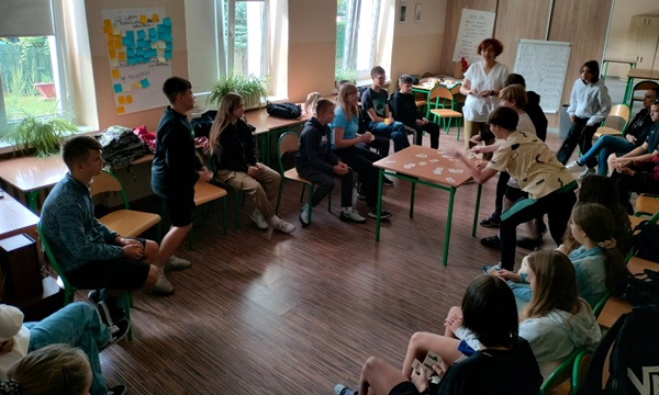 uczniowie siedzą na krzesłach w kole