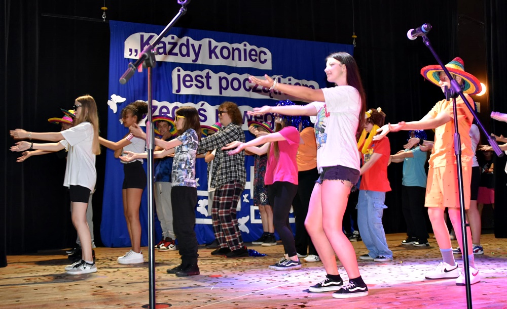 dzieci w kolorowych strojach występują na scenie domu kultury