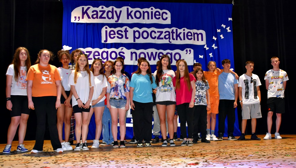 dzieci w kolorowych strojach występują na scenie domu kultury