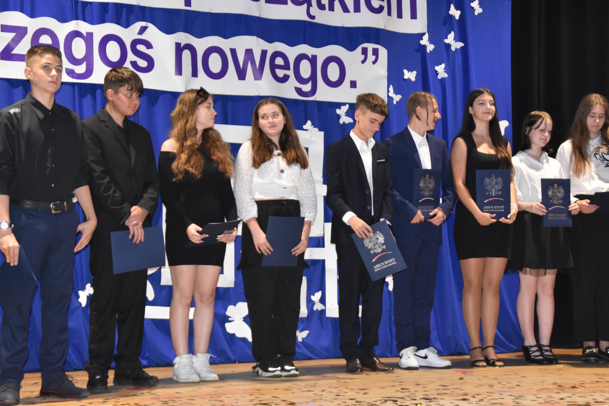 dzieci w kolorowych strojach występują na scenie domu kultury
